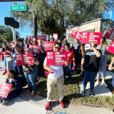 Nurses in from of HCA Florida Osceola Hospital holding signs "Hey HCA, put patients over profits"