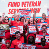 Group of nurses with raised fists holding signs supporting veterans and VA nurses