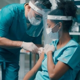 Nurse administering vaccine on another nurse