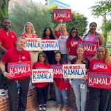 Group of nurses holding red and white "Nurses for Kamala" signs