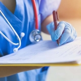 Nurse with clipboard signing document