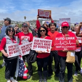 Group of nurses outside, holding signs "Our Patients Rights Have No Borders"