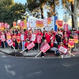 Large group of nurses outside hospital holding signs calling for safe staffing