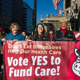 Four nurses outside holding banner "Vote YES to Fund Care"