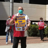 Nurses and hospital staff hold signs calling for prioritizing safety for staff anbd the public