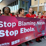 Large group of nurses holding sign "Stop Ebola Now"