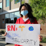 Nurse holds signs "RNs Global Solidarity"