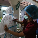 A nurse draws a smiley face on the back of a fellow health worker